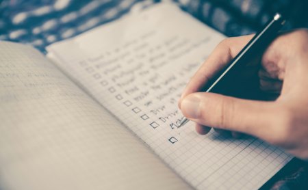 Hand schreibt eine Zielliste in ein Notizbuch