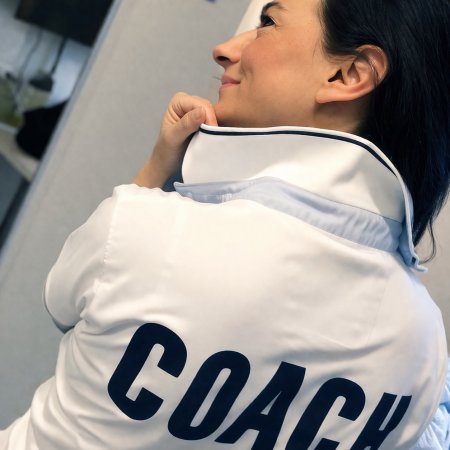 Donna con colletto alzato indossa giacca con scritta COACH sulla schiena